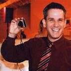 Adam wearing tie, smiling and holding camera